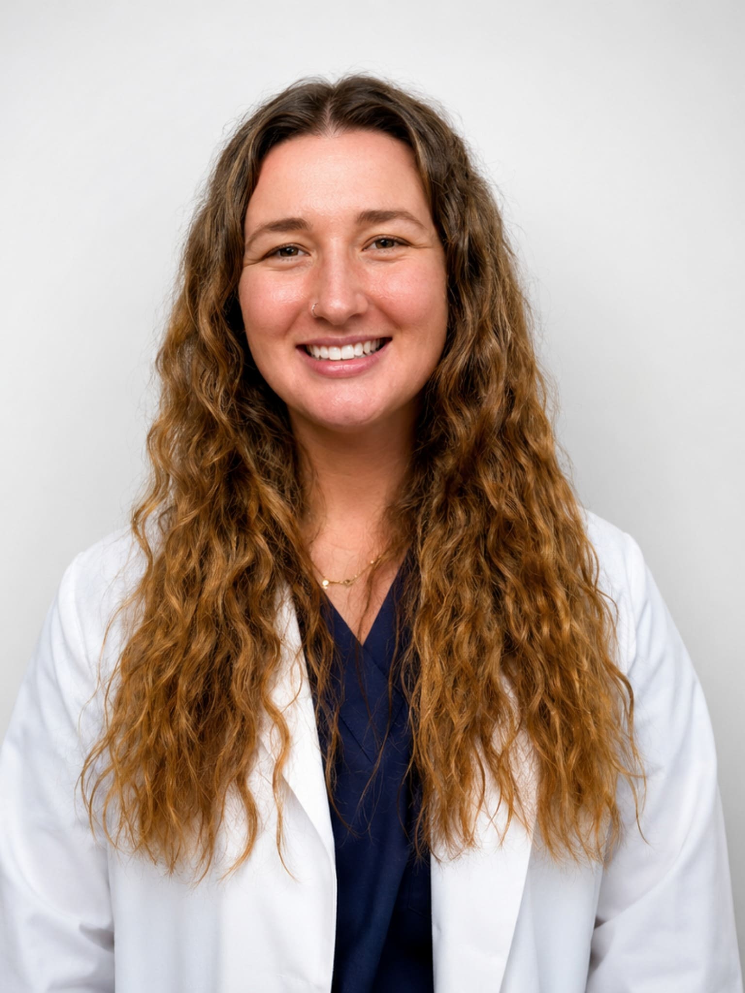 Dr. Daley Mcghee female veterinarian with long brown curly hair wearing a white lab coat