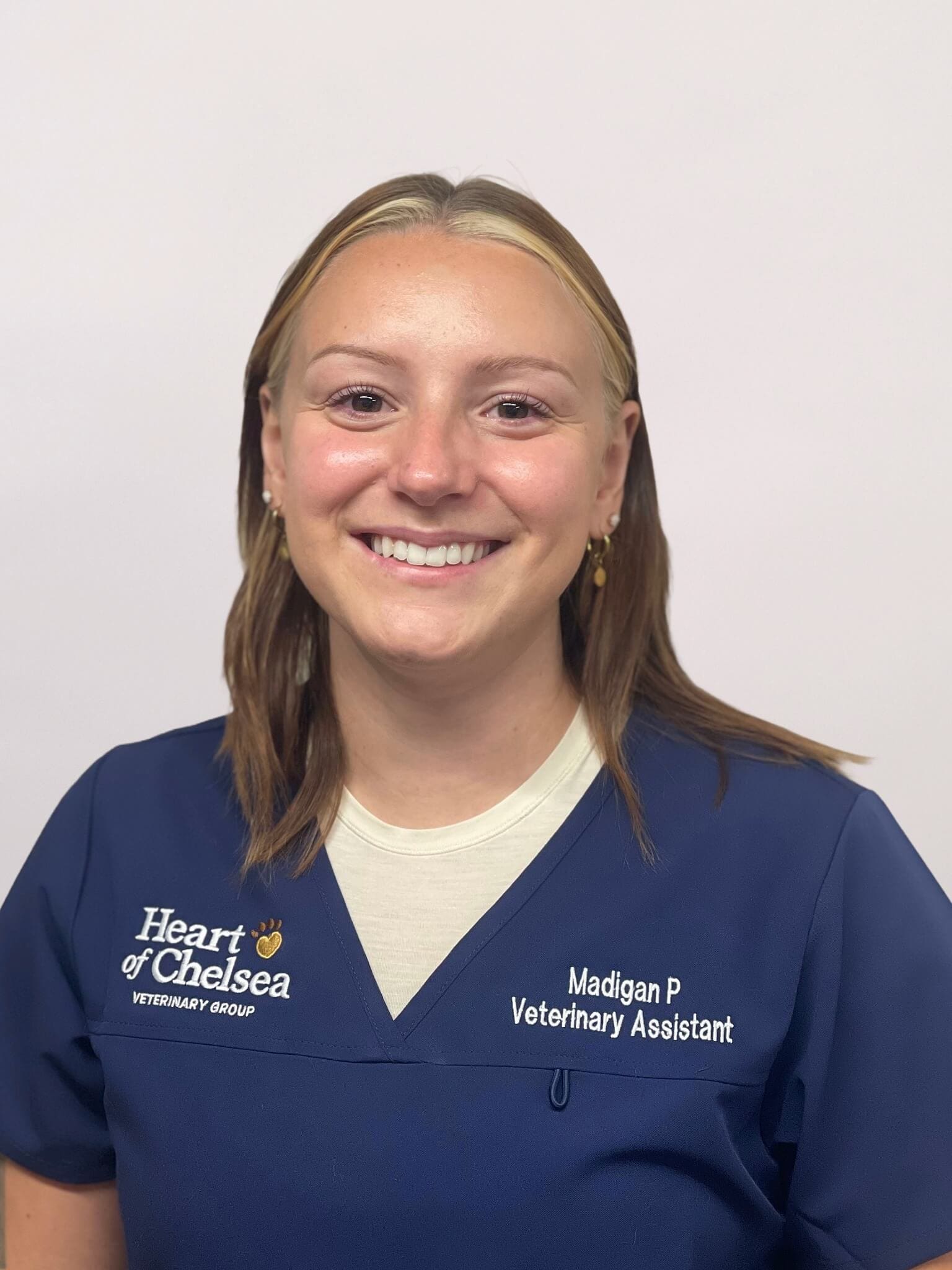 Female with should length hair wearing a blue v-neck scrub shirt and a yellow shirt underneath